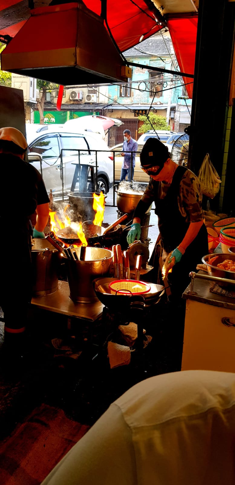 Koks bereiden gerechten boven hoog vuur in een levendige straatkeuken in Bangkok